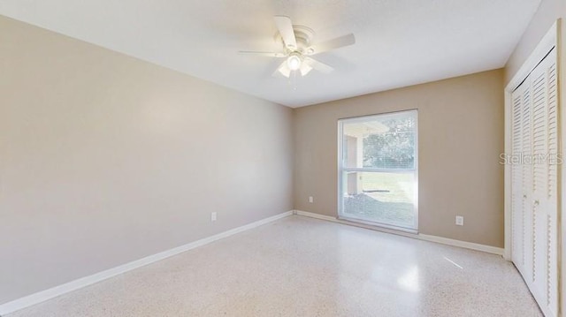 spare room featuring baseboards, light speckled floor, and a ceiling fan