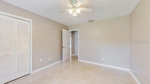 unfurnished bedroom featuring baseboards, visible vents, ceiling fan, speckled floor, and a closet