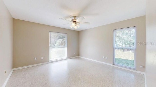 unfurnished room featuring baseboards, a ceiling fan, and speckled floor