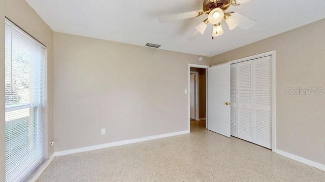 unfurnished bedroom featuring baseboards, visible vents, light speckled floor, and a closet