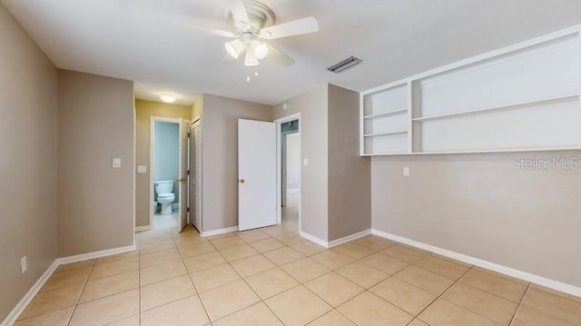 empty room with a ceiling fan, visible vents, baseboards, and light tile patterned floors