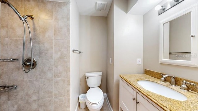 bathroom with toilet, tiled shower, and vanity