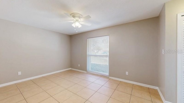 empty room with light tile patterned flooring, ceiling fan, and baseboards