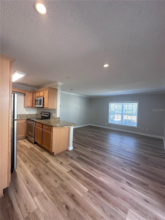 kitchen with baseboards, light wood-style flooring, appliances with stainless steel finishes, open floor plan, and ornamental molding