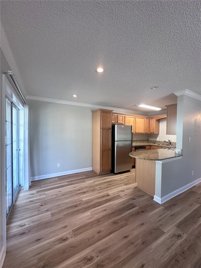 kitchen with light wood-style flooring, crown molding, and freestanding refrigerator