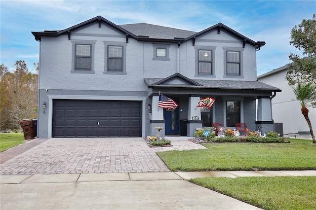 view of front of home featuring decorative driveway, stucco siding, an attached garage, a front yard, and central AC