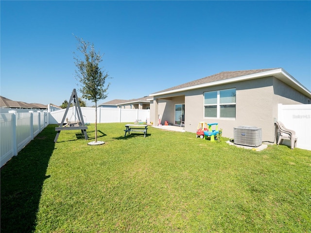 back of property featuring a shingled roof, a fenced backyard, a yard, central air condition unit, and stucco siding