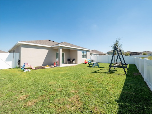 back of house featuring a lawn, a fenced backyard, and stucco siding