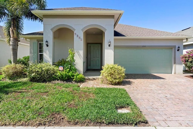 view of front of property with decorative driveway, roof with shingles, an attached garage, and stucco siding