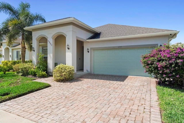 view of front of house featuring a garage, decorative driveway, a shingled roof, and stucco siding