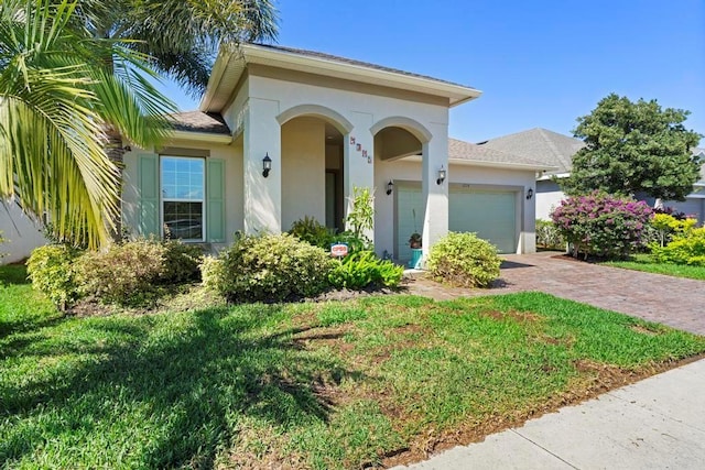 mediterranean / spanish-style house featuring an attached garage, a front lawn, decorative driveway, and stucco siding