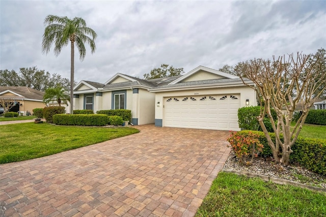 ranch-style home featuring stucco siding, an attached garage, decorative driveway, and a front lawn