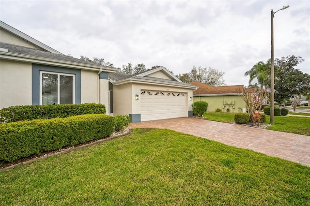 ranch-style house with a front yard, a garage, driveway, and stucco siding