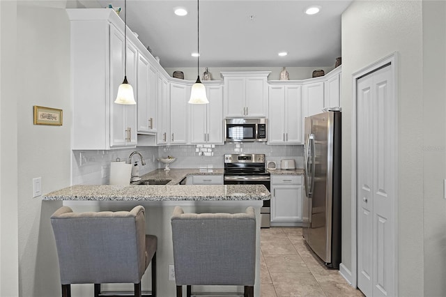 kitchen with stainless steel appliances, a peninsula, a sink, and decorative backsplash