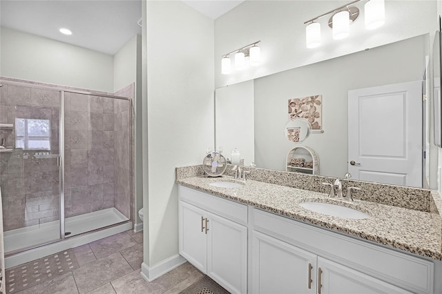 full bath featuring double vanity, a shower stall, toilet, and a sink