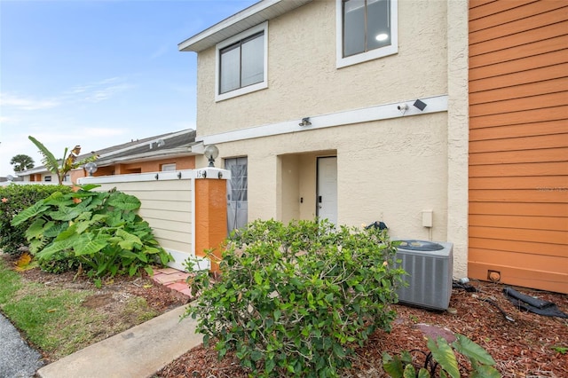 property entrance with cooling unit and stucco siding