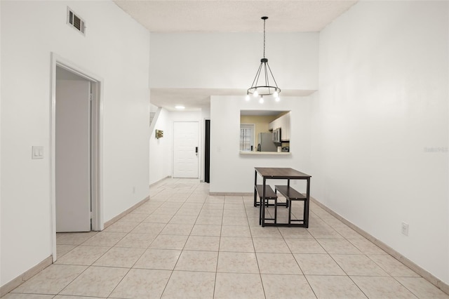 unfurnished dining area featuring visible vents, a textured ceiling, baseboards, and light tile patterned floors