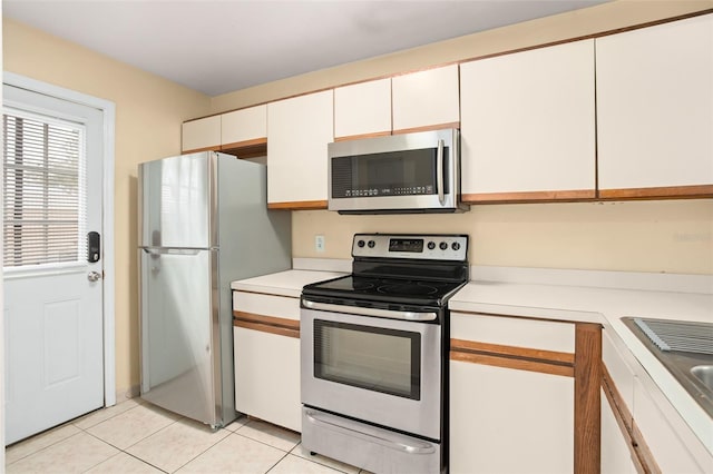 kitchen featuring light tile patterned floors, stainless steel appliances, light countertops, and white cabinets