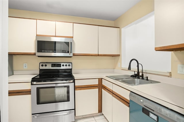 kitchen featuring light tile patterned floors, light countertops, appliances with stainless steel finishes, and a sink