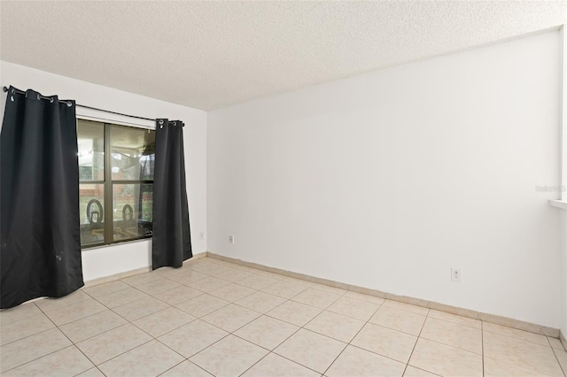 empty room with a textured ceiling and light tile patterned floors