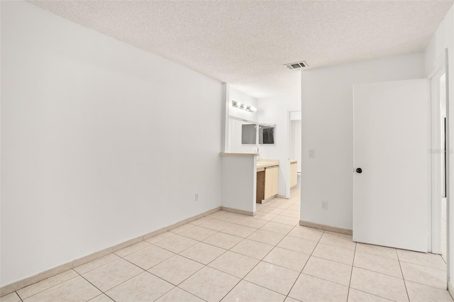 unfurnished room featuring visible vents, a textured ceiling, and light tile patterned flooring