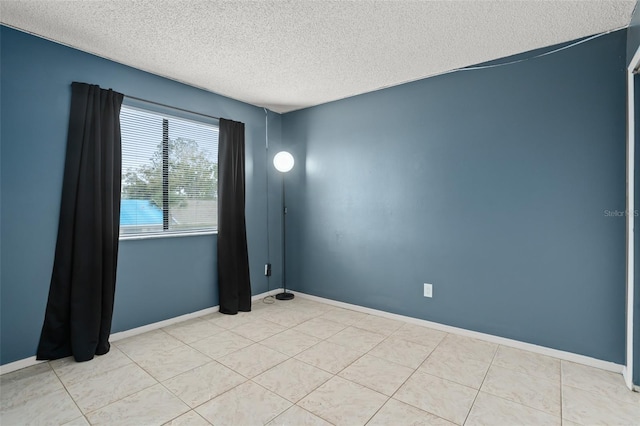 empty room with a textured ceiling, baseboards, and light tile patterned floors