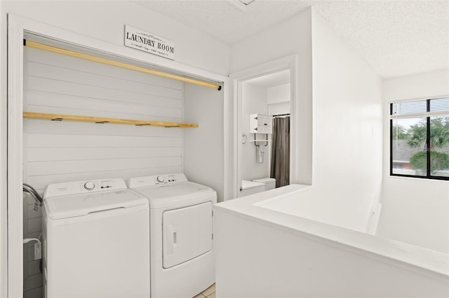 clothes washing area with washer and dryer, laundry area, and a textured ceiling