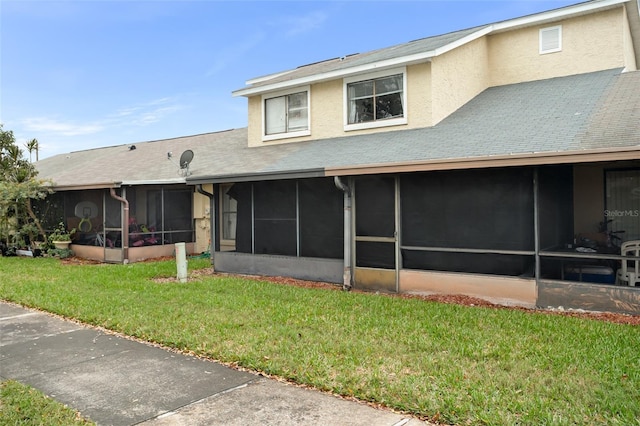 back of property with a sunroom, a lawn, and stucco siding