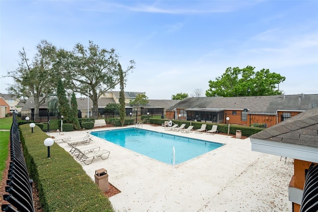 community pool featuring a yard, a patio area, and fence