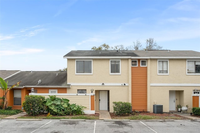 view of front facade featuring uncovered parking, central AC, and stucco siding