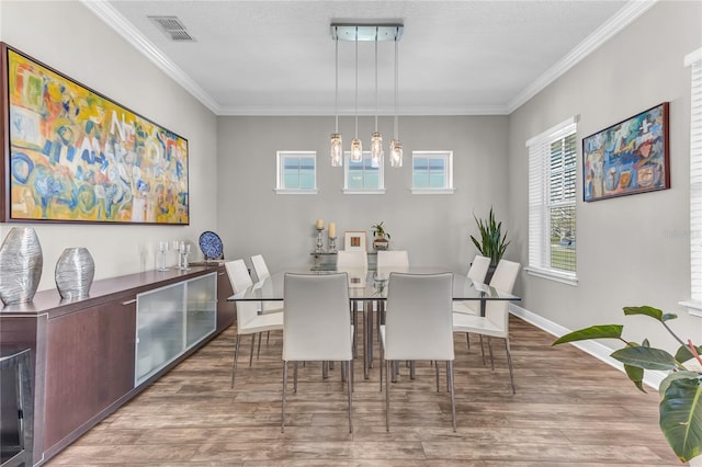 dining area with ornamental molding, wood finished floors, visible vents, and baseboards