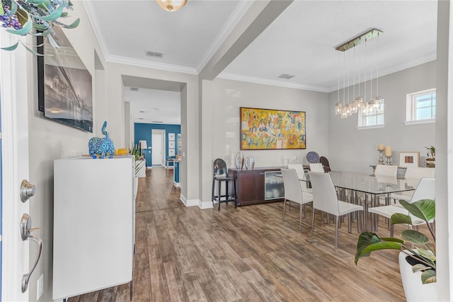 dining area featuring visible vents, crown molding, baseboards, and wood finished floors