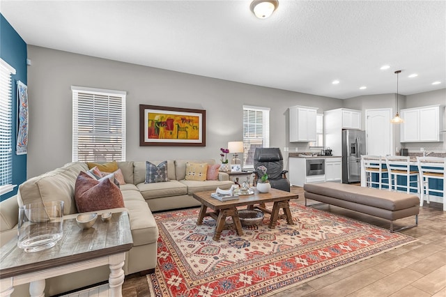 living area featuring light wood-style floors, recessed lighting, and a textured ceiling