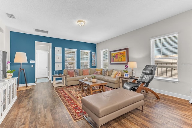 living room featuring wood-type flooring, visible vents, and a textured ceiling