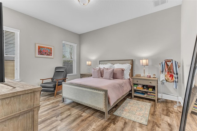 bedroom with light wood-style floors, visible vents, and baseboards