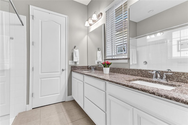 bathroom featuring double vanity, tiled shower, tile patterned flooring, and a sink