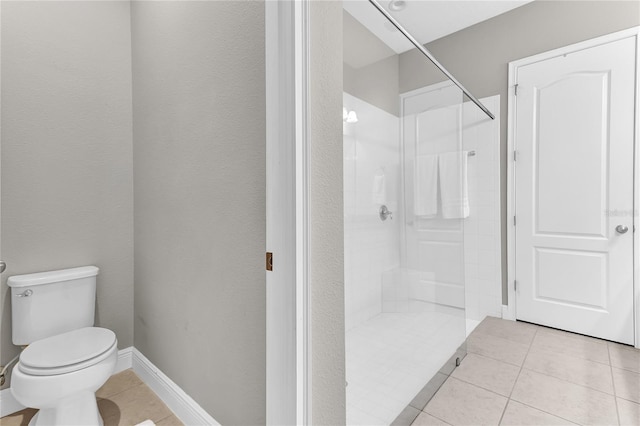 bathroom featuring toilet, baseboards, a walk in shower, and tile patterned floors