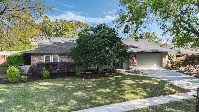 view of front of house with fence, concrete driveway, a front yard, roof with shingles, and stone siding