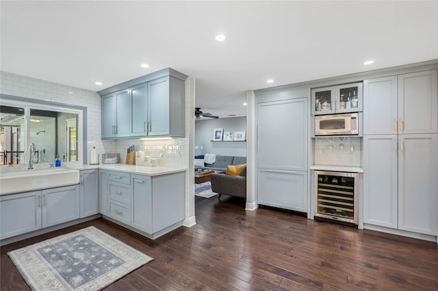 kitchen featuring gray cabinetry, wine cooler, built in microwave, dark wood-style floors, and a sink