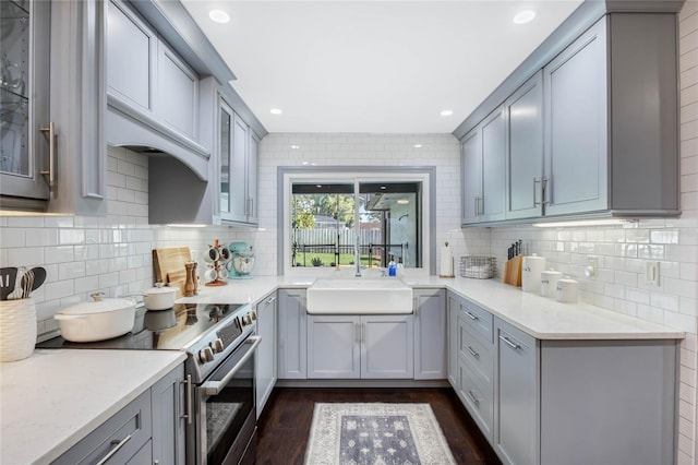 kitchen featuring a sink, stainless steel electric range, gray cabinets, and light countertops