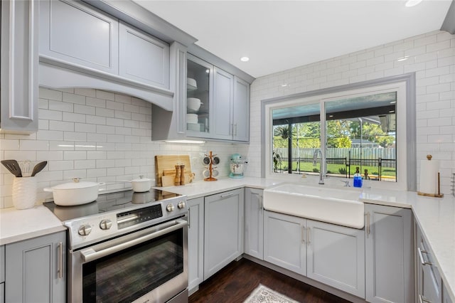 kitchen with electric range, gray cabinetry, backsplash, and a sink