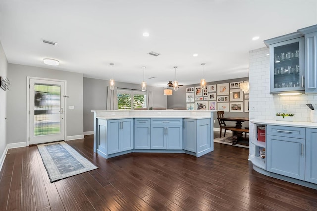 kitchen featuring light countertops, dark wood-style floors, visible vents, and a center island