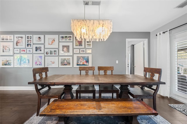 dining space with an inviting chandelier, dark wood-type flooring, baseboards, and visible vents