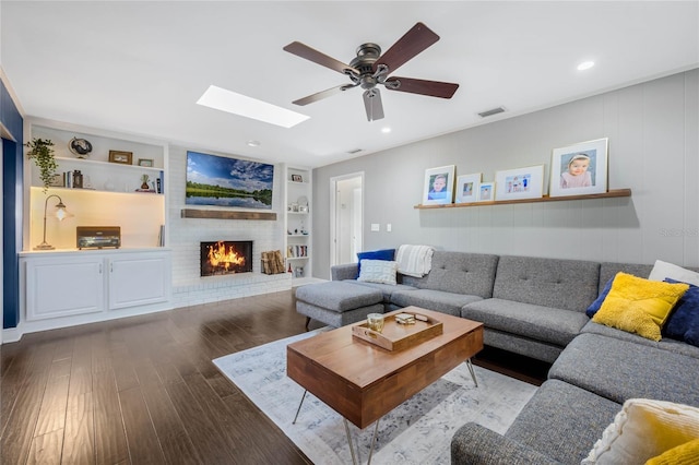 living area featuring visible vents, built in features, wood finished floors, a skylight, and a fireplace