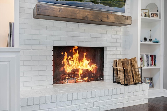 interior details with a brick fireplace, built in features, wood finished floors, and baseboards