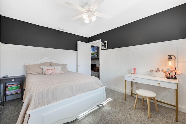 bedroom with a wainscoted wall, carpet flooring, a ceiling fan, and visible vents