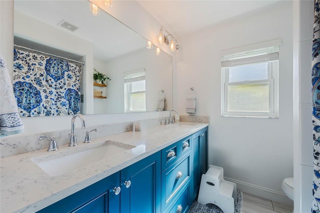 bathroom with double vanity, toilet, visible vents, and a sink