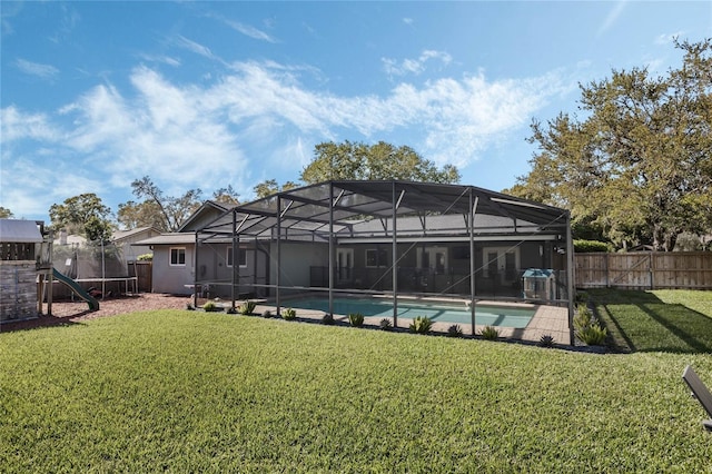 rear view of property with a fenced backyard, a fenced in pool, a lawn, and a trampoline