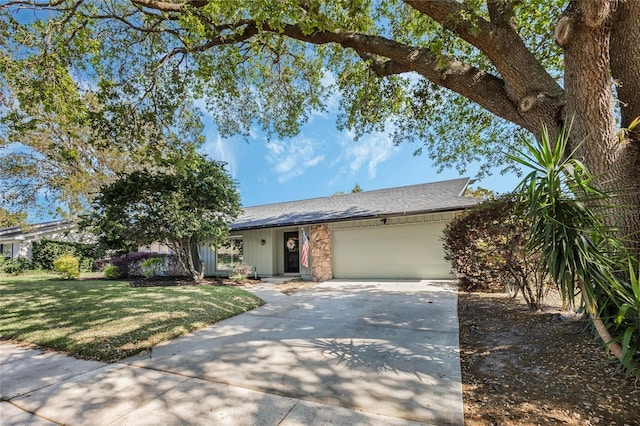 ranch-style house featuring a front yard, concrete driveway, a garage, and a shingled roof