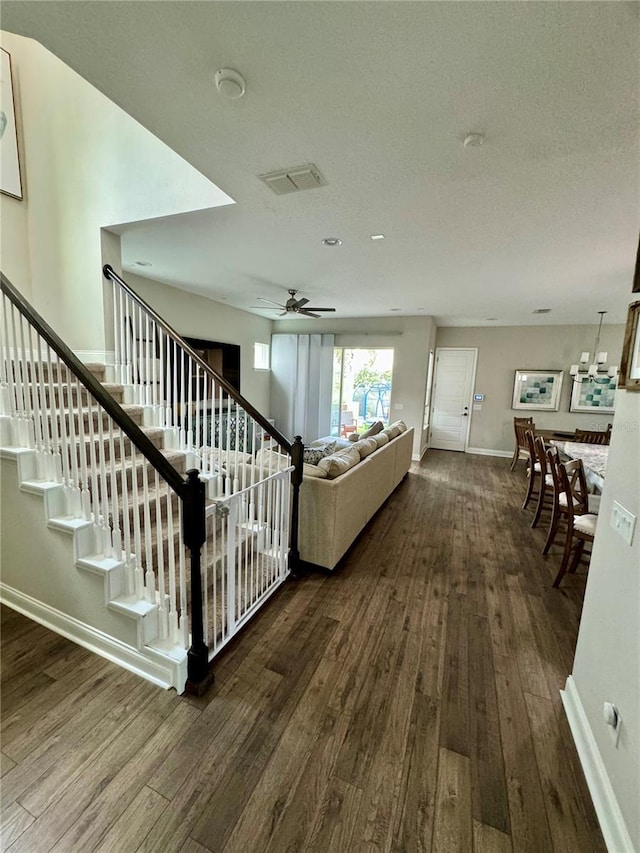 unfurnished living room featuring stairs, ceiling fan, baseboards, and wood finished floors